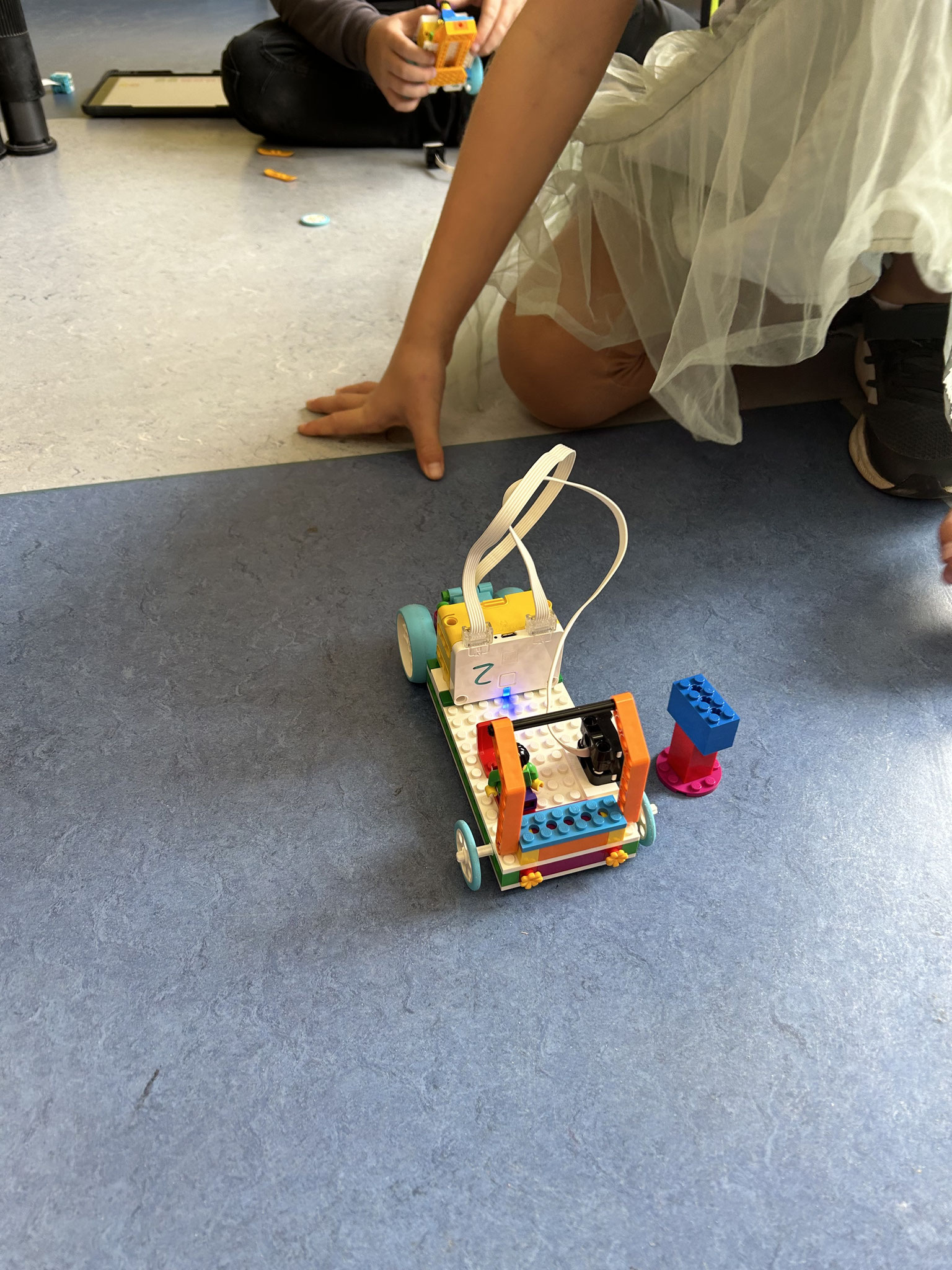 AG-Angebote an der Alteburgschule Kleines Lego-Fahrzeug mit bunten Bausteinen wird auf dem Boden bewegt.