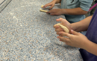 Kinder formen Hefeteig auf einer Küchenarbeitsfläche.