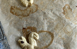Ungebackene Hefeteigfiguren auf Backpapier, bereit zum Backen.