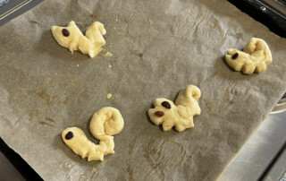 Roh geformte Hefeteigfiguren liegen auf einem Backblech mit Backpapier.