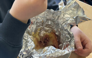 Bratapfel in Alufolie wird von einem Kind mit einem Löffel gegessen.