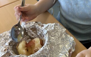 Kind isst einen Bratapfel, der in Alufolie serviert wird.