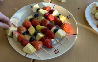 Teller mit bunten Obstspießen auf einem Tisch.