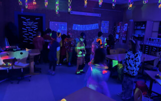 Partyraum mit bunter Beleuchtung und mehreren Kindern, die tanzen.