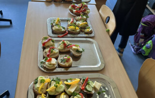 Mehrere Tabletts mit verschieden belegten Brötchen stehen auf einem Tisch.
