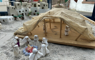 Miniaturszene mit Figuren vor einem großen künstlichen Felsen und Sandfläche.