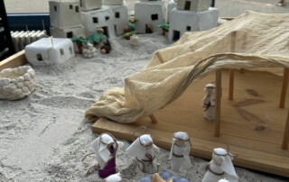 Kleine weiße Figuren stehen vor einer modellierten Felslandschaft und Stadt aus Miniaturhäusern.