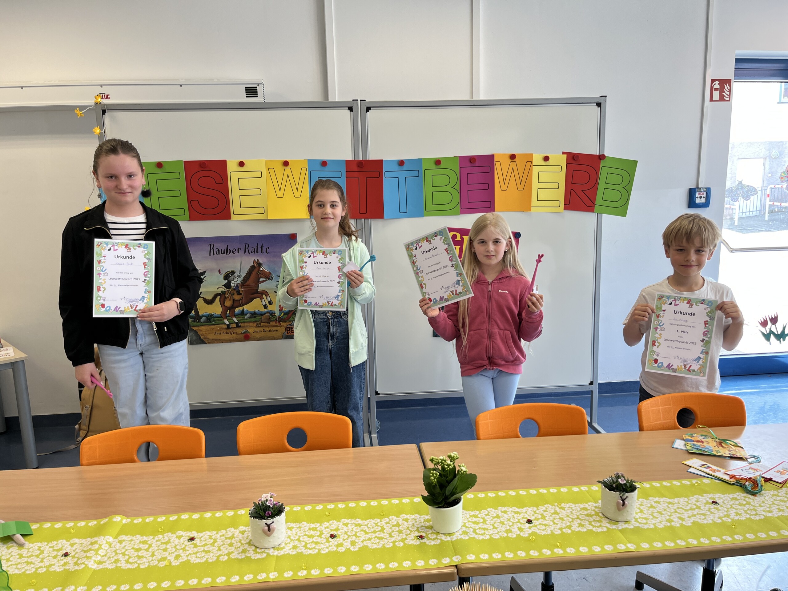 Mehrere Kinder stehen im Klassenraum und halten gestaltete Blätter in die Höhe.