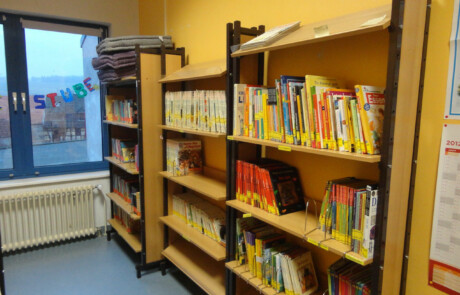 Innengebäude Nahaufnahme eines Bücherregals in der Schulbücherei mit bunten Kinder- und Jugendbüchern