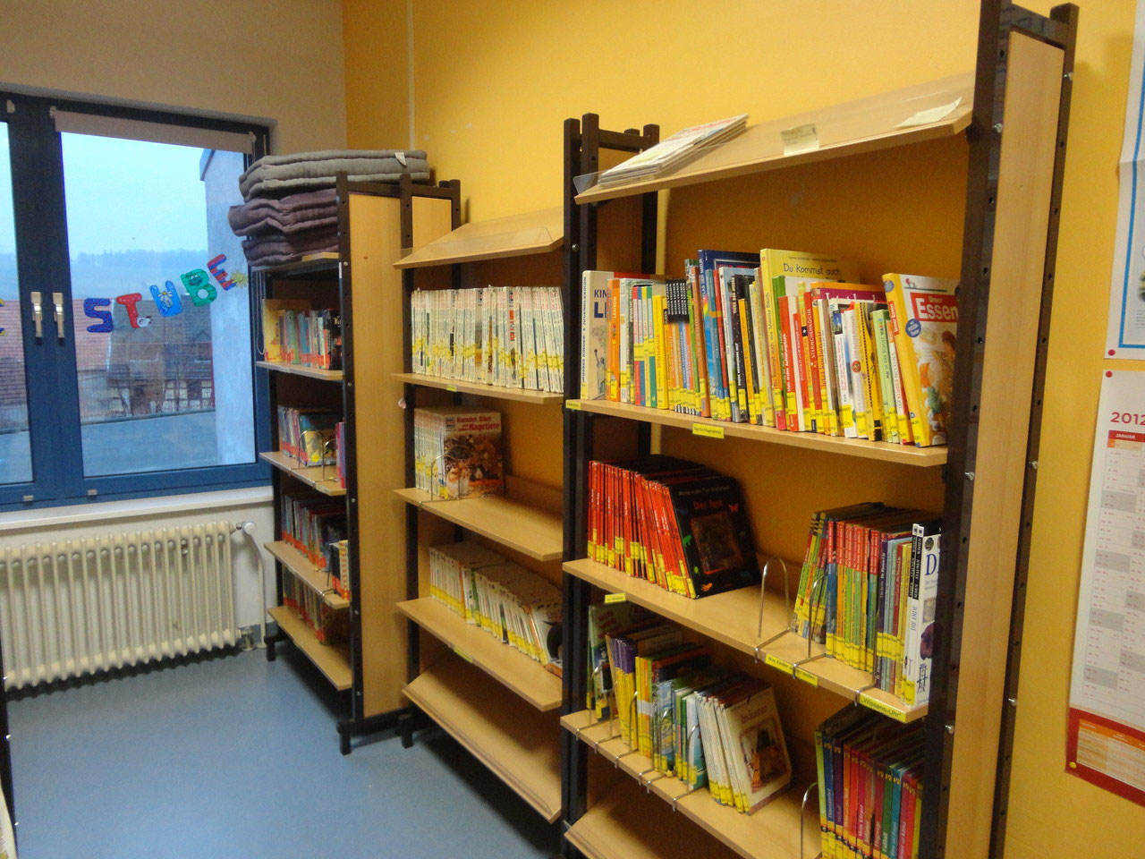 Nahaufnahme eines Bücherregals in der Schulbücherei mit bunten Kinder- und Jugendbüchern