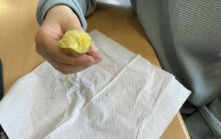 Kind legt eine geschälte Kartoffel auf ein Papiertuch.