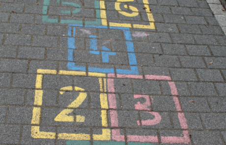 Pausenhof Hüpfspiel „Himmel und Hölle“ in bunten Kreidefeldern auf dem gepflasterten Boden.