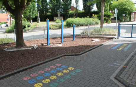 Pausenhof Spielplatz mit bunten Punkten auf dem Boden als Bewegungsspiel.