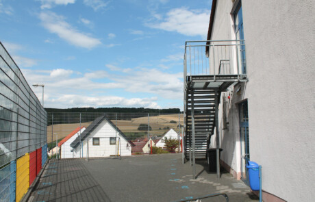 Pausenhof Hinterhof mit Metalltreppe und Blick über die umliegenden Häuser.