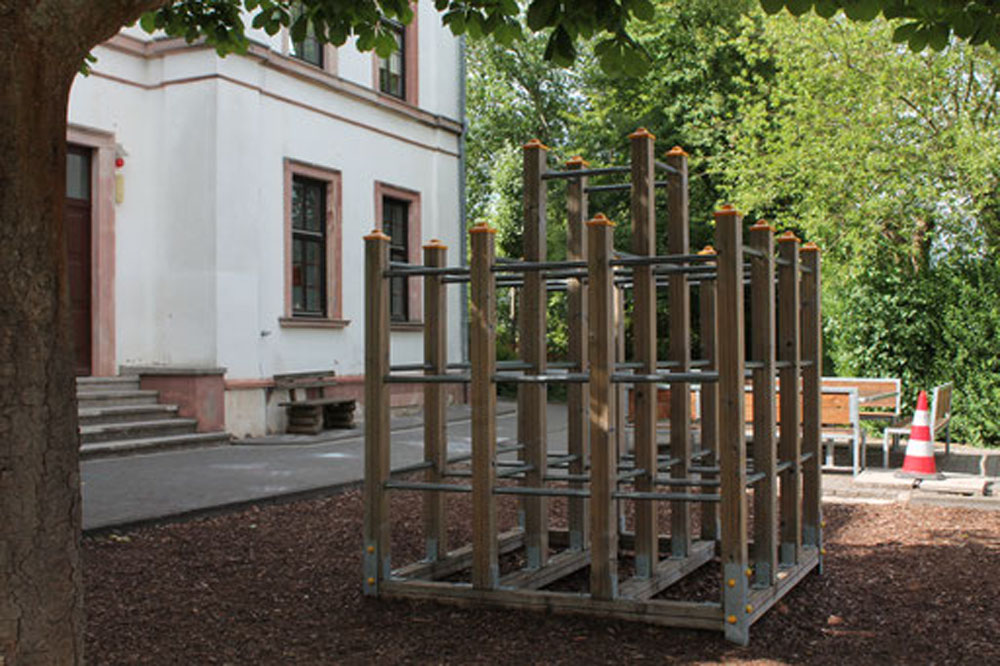 Außenaufnahme der Alteburgschule Heftrich mit Klettergerüst im Vordergrund.
