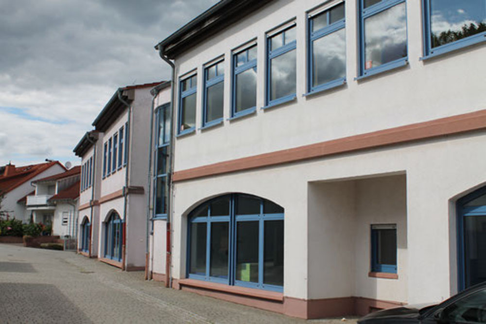 Moderne Glasfront eines Schulgebäudeteils mit blauem Rahmen.