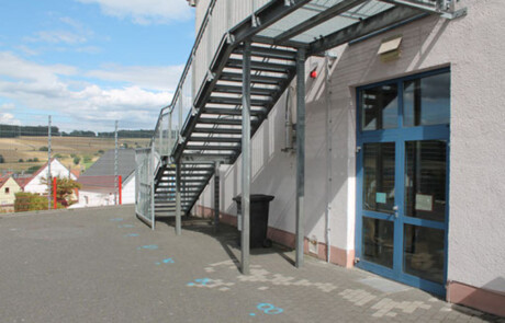 Schulgebäude_11 Metalltreppe und Eingang an der Rückseite eines Schulgebäudes.