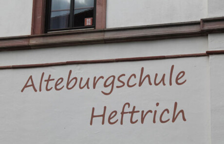Schulgebäude_12 Nahaufnahme der Hauswand der Alteburgschule Heftrich mit Schriftzug.
