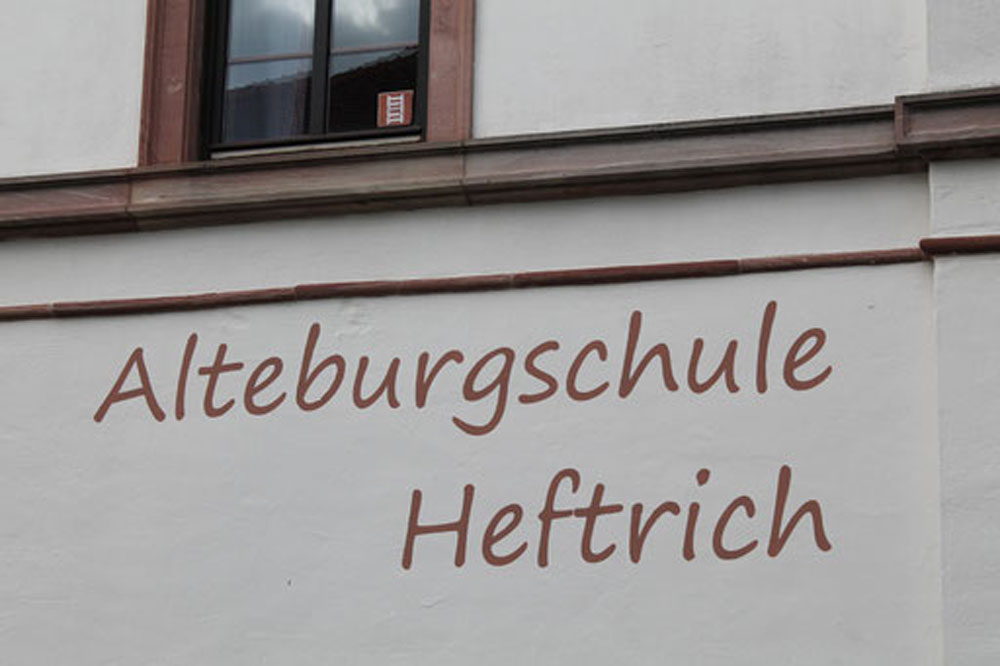 Nahaufnahme der Hauswand der Alteburgschule Heftrich mit Schriftzug.