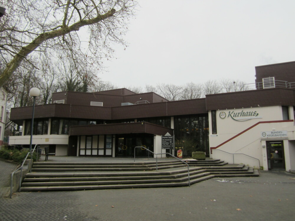 Außenansicht eines Schulgebäudes mit Treppe und überdachtem Eingangsbereich an einem bewölkten Tag