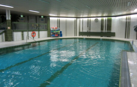 Schwimmbecken (von der anderen Seite) Innenaufnahme eines Hallenbads mit großem Schwimmbecken und umlaufenden Fenstern