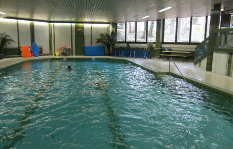 Schwimmbecken (leer) Leeres Schwimmbecken in einer Halle mit breiten Fenstern und hellen Wänden.