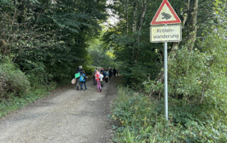 Kinder laufen auf einem breiten Waldweg bergauf.