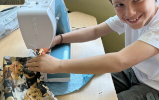 Kind arbeitet an einer Nähmaschine und führt Stoff unter die Nadel.