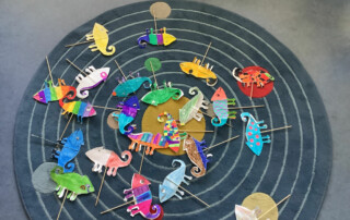 Ausstellung von zahlreichen Schülerarbeiten auf farbigen Plakaten im Klassenraum.