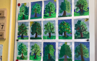 Schwarzer Stoffhintergrund mit daran befestigten bunten Papierblumen und Figuren.